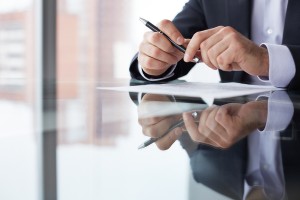 Close-up of male hands with pen over document