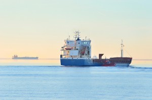 Cargo ship sailing away against colorful sunset